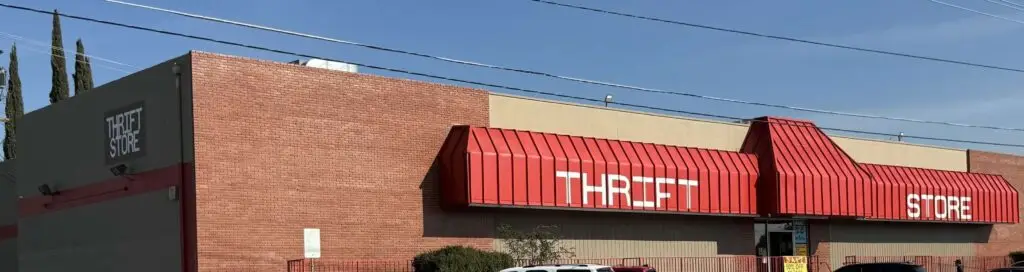 Commercial building with red metal paint, darker tan stucco, new sign lettering, and parking lot stripes.