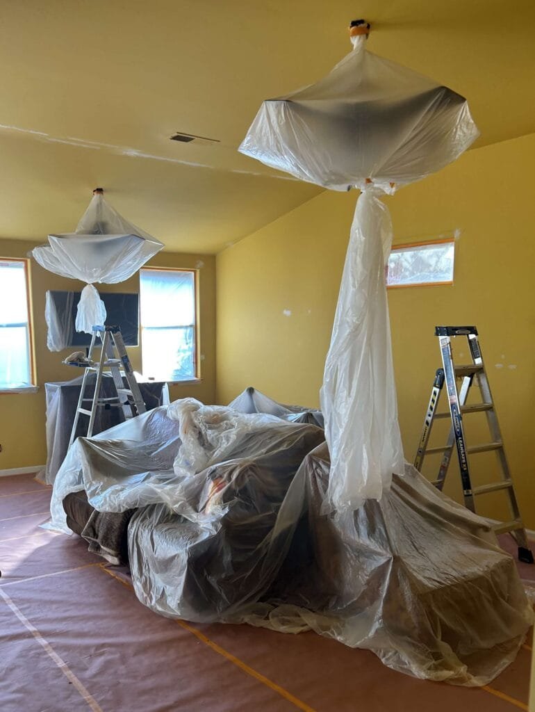Furniture and electronics covered in living room for interior wall and ceiling painting in Bakersfield, CA.