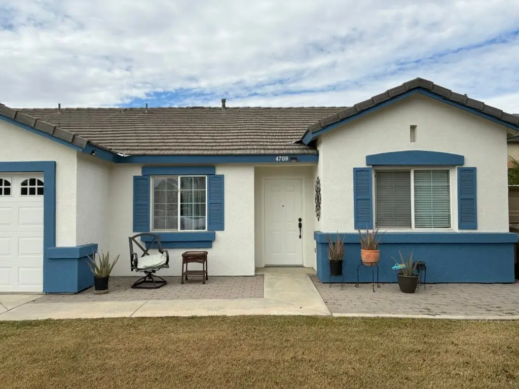 Stucco home with freshly painted white walls and blue fascia.