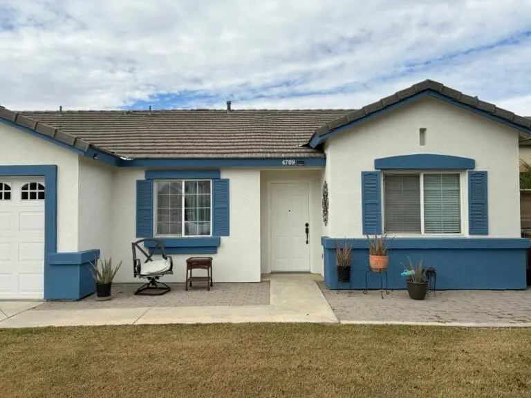 Stucco home with freshly painted white walls and blue fascia.