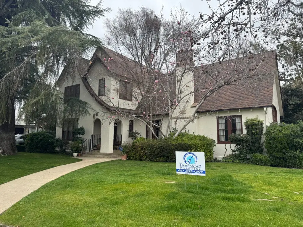 Front exterior of white stucco home with brown fascia and landscaping.